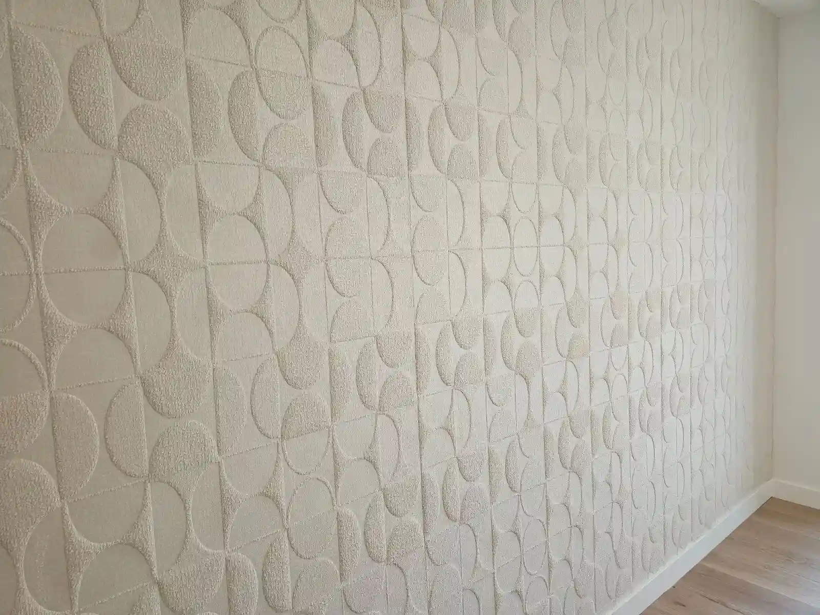 Pale textured geometric wallcovering above a light wood floor.